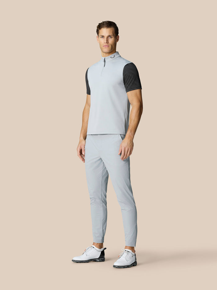 Full body shot of a man in a light grey sleeveless golf gilet with matching pants and white golf shoes