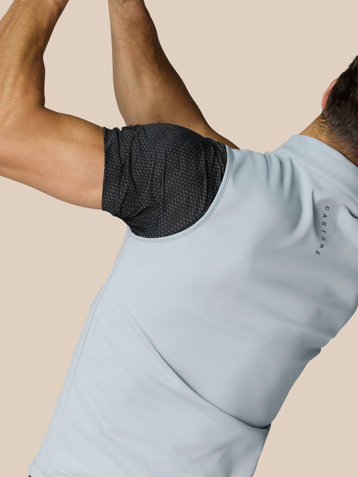 Side view of a man wearing a light grey golf half zip gilet over a dark dotted underlayer