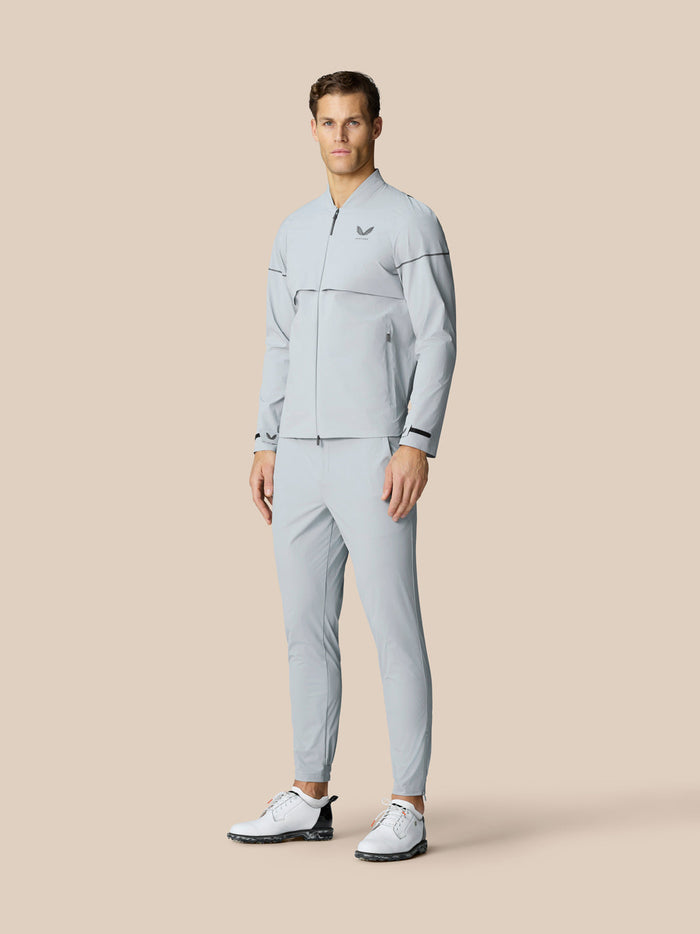 Full body shot of male model in light grey Golf Pinnacle LVS Woven Jacket with matching pants and white golf shoes