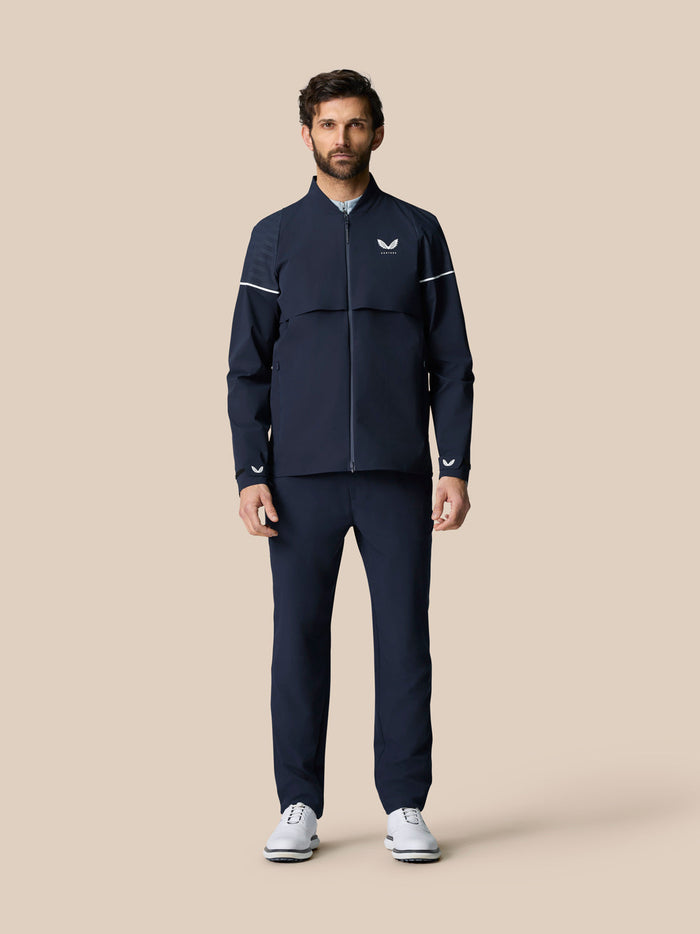Model wearing Golf Pinnacle LVS Woven Jacket in midnight navy with zip front and white chest logo