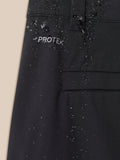 Close-up of black golf trouser fabric with ProTek logo and water droplets near a pocket seam