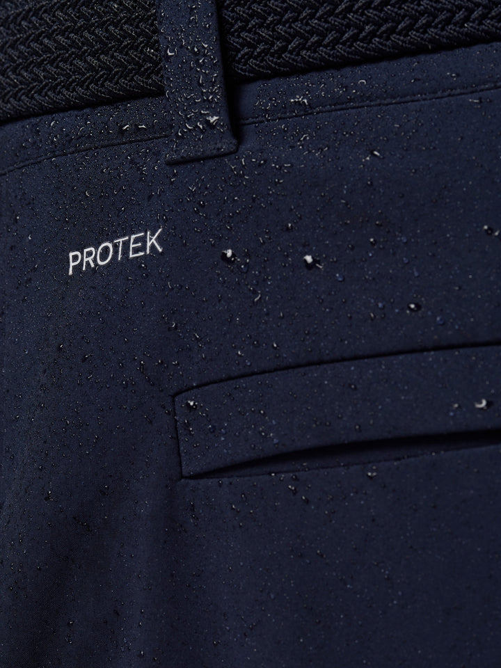 Close up of midnight navy golf trouser fabric with ProTEK branding and water droplets