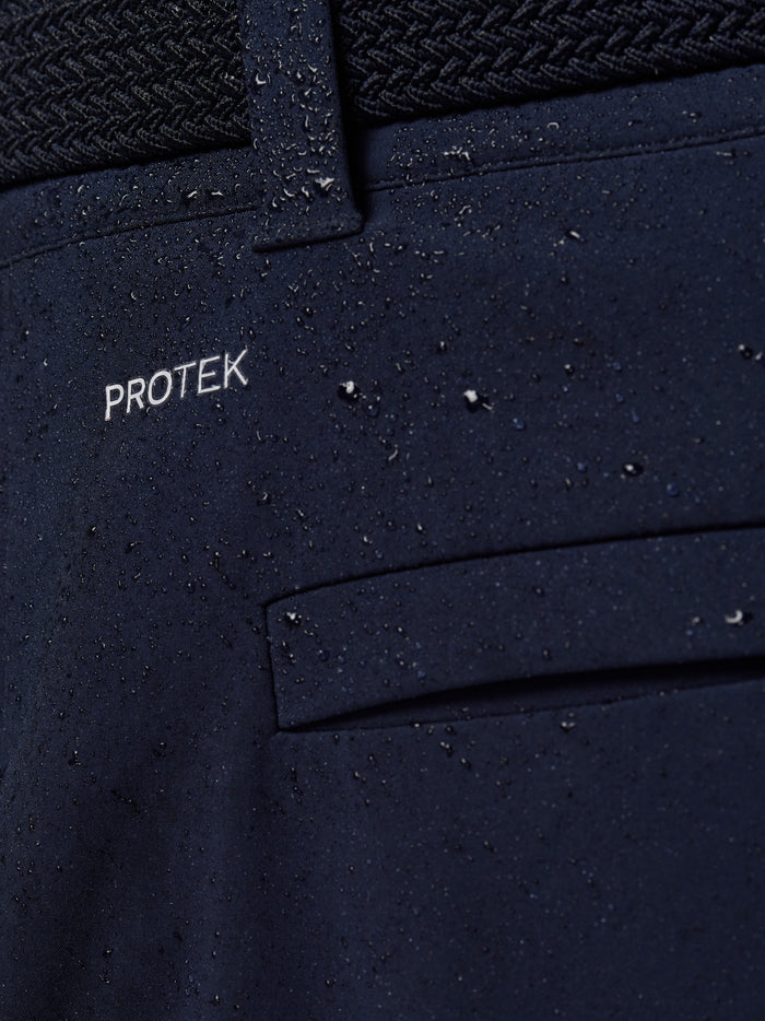 Close-up of navy golf trouser fabric with water droplets and ProTek branding.