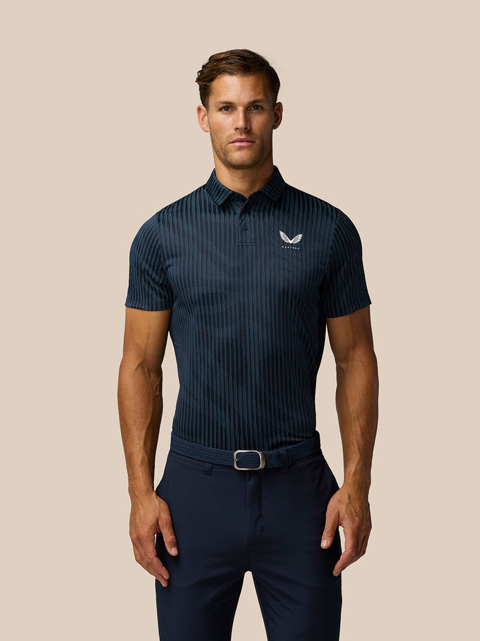 Male model wearing Golf Pinnacle Glow Polo in midnight navy with a striped knit and left chest logo.