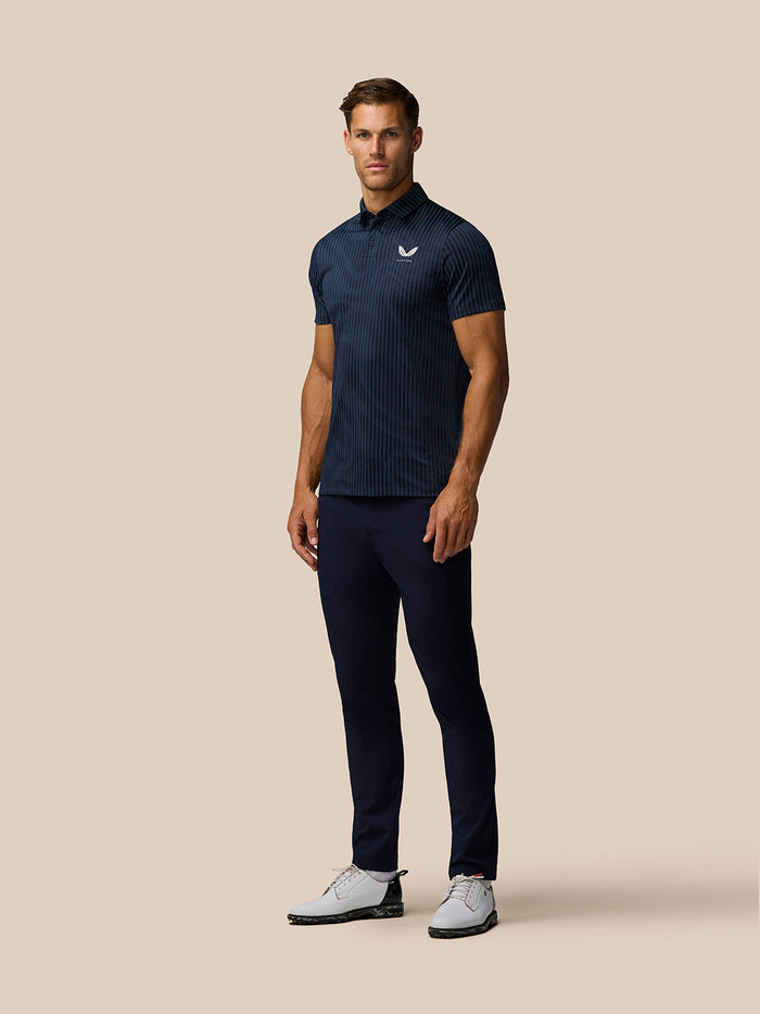 Front view of a man in a navy striped golf polo with Castore logo on the left chest, paired with navy pants.