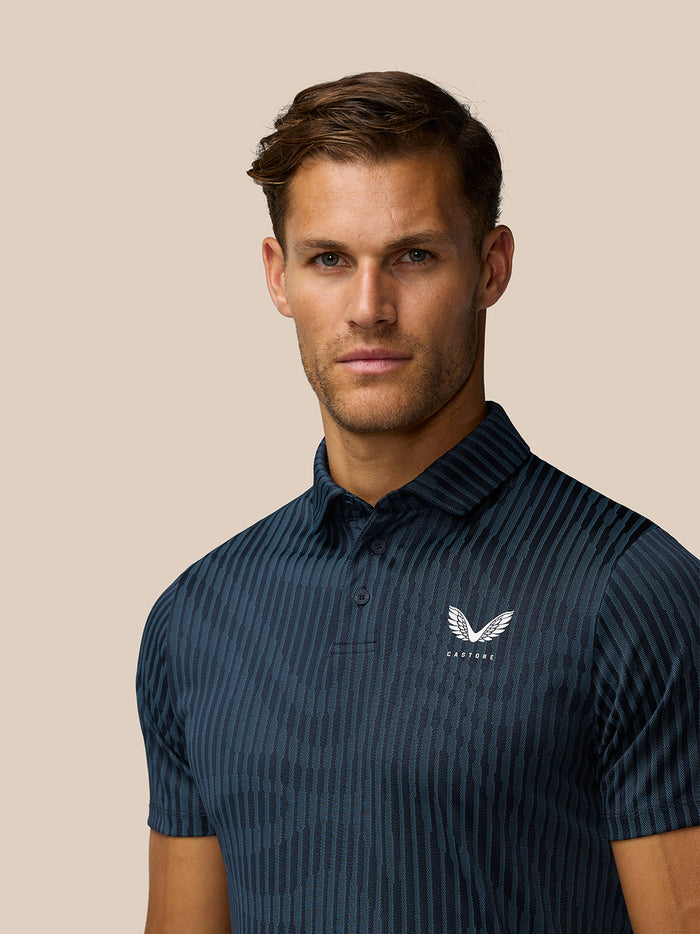 Close-up of midnight navy Golf Pinnacle Glow Polo showing striped knit and left chest Castore logo.