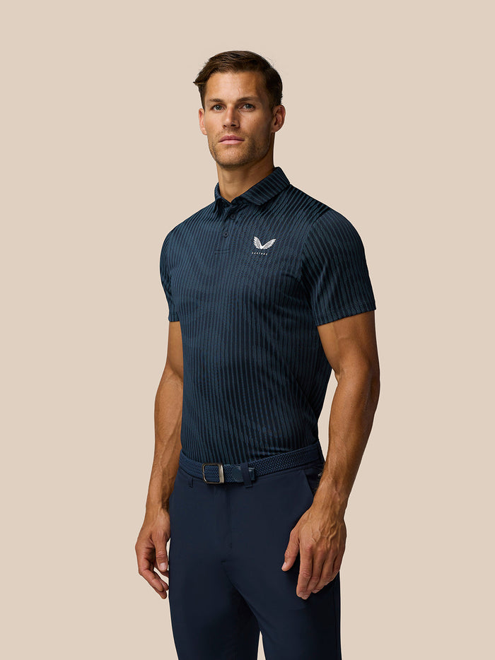 Male model in a midnight navy striped golf polo with a small chest logo and polo collar, paired with dark navy pants.