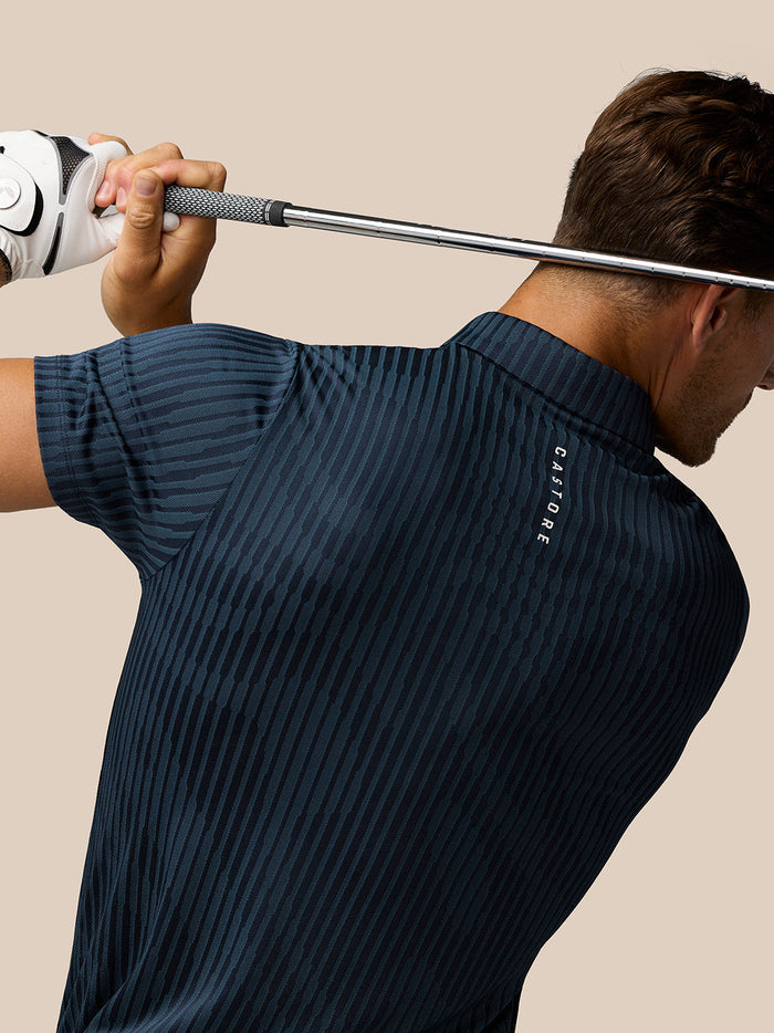 Back view of a man wearing midnight navy Golf Pinnacle Glow Polo with Castore branding along the back.