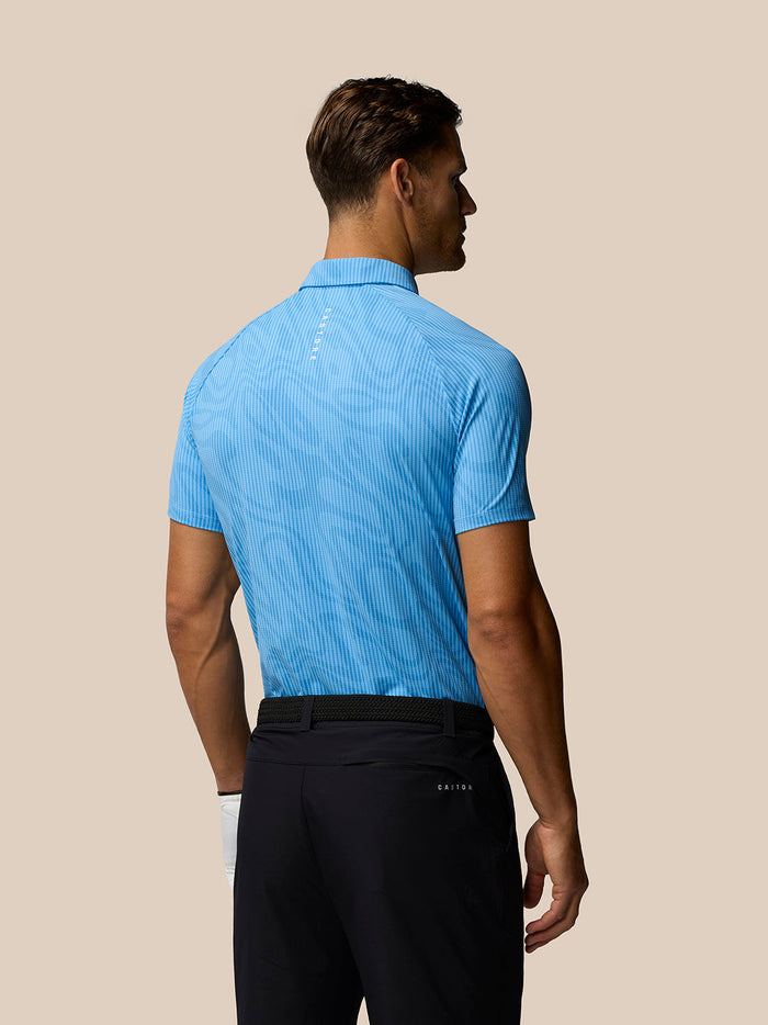 Back view of a male model wearing Golf Club Glow Printed Polo in blue with a subtle pattern.