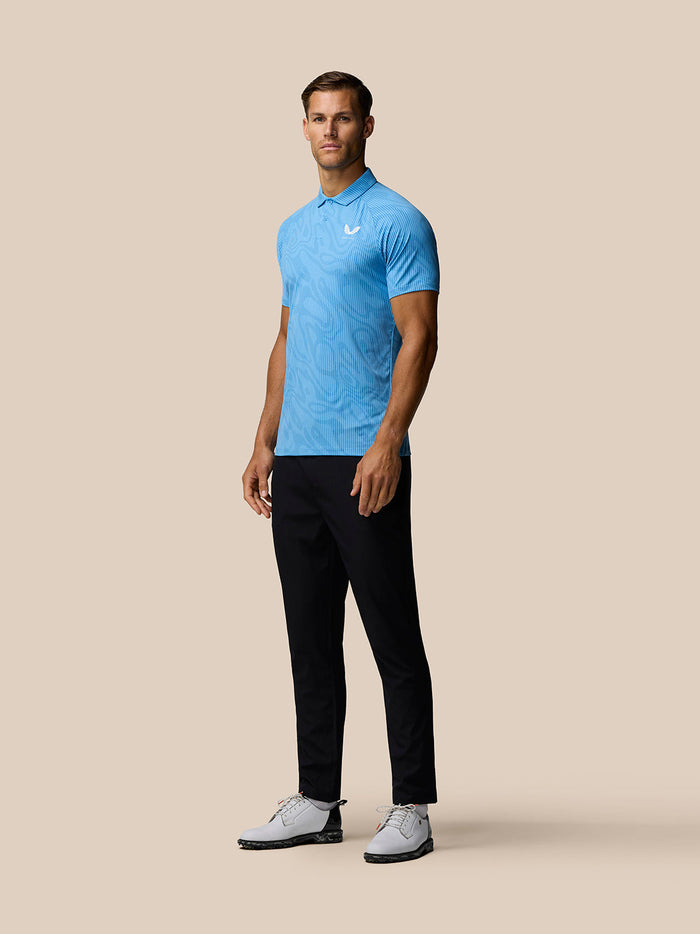 Male model wearing light blue Golf Club Glow Printed Polo with a white Castore logo on the chest.