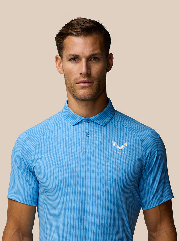 Close up of Golf Club Glow Printed Polo in blue showing a white Castore logo on the chest.