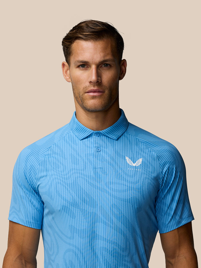 Close up of Golf Club Glow Printed Polo in blue showing a white Castore logo on the chest.