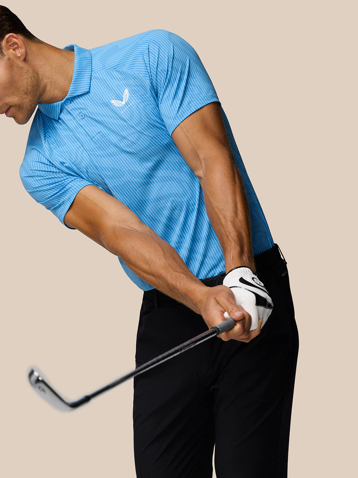 Golfer wearing a Cool Blue Glow Printed Polo during a swing, showing striped texture and Castore logo on the chest