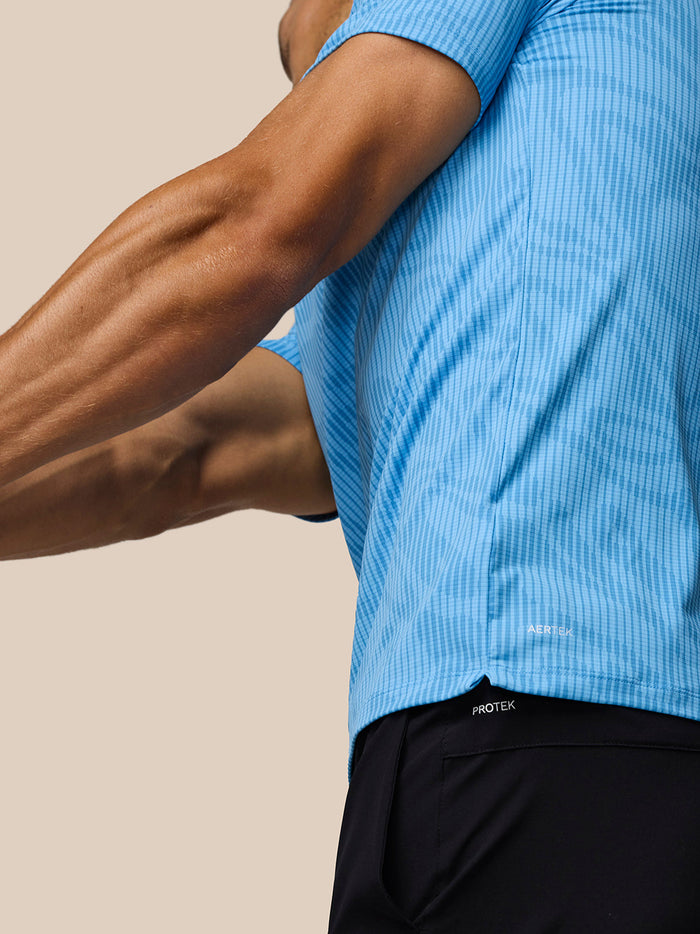 Side view of a man wearing a Cool Blue Glow Printed Polo with AerTek fabric and left chest Castore logo