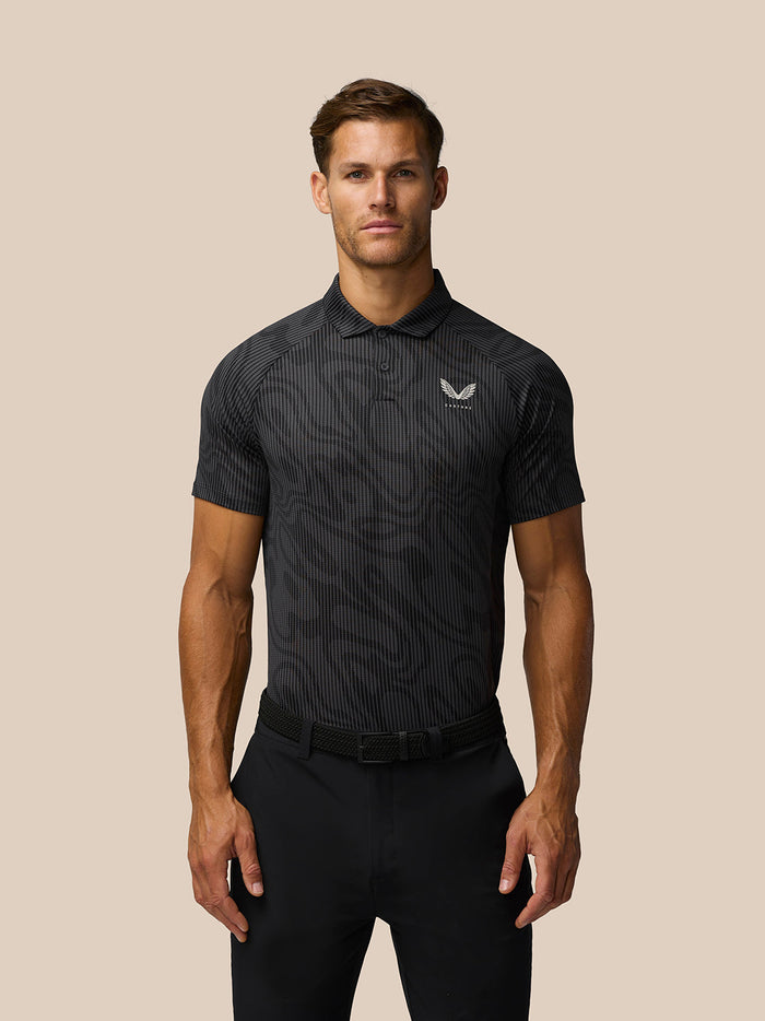 Male model wearing gunmetal grey golf polo with subtle printed pattern, short sleeves, collar, and left chest logo.