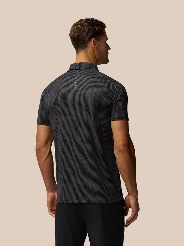 Back view of a man wearing a gunmetal grey golf polo with a subtle zebra stripe pattern.