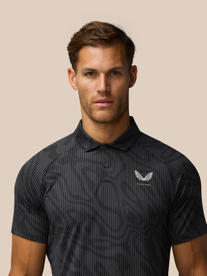 Close-up of a man wearing a gunmetal grey striped golf polo with Castore logo on the left chest.