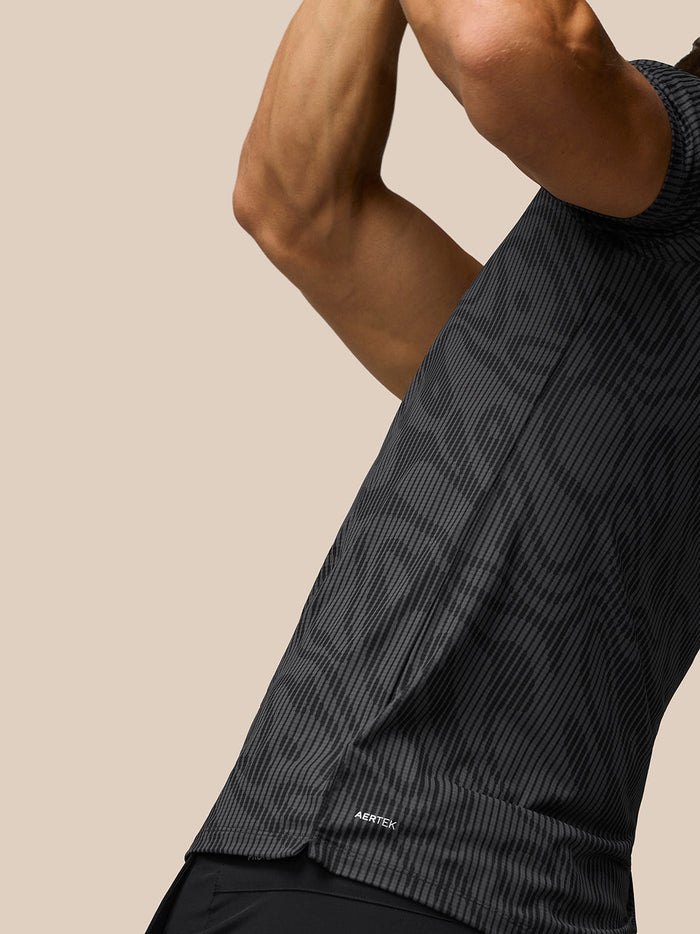 Close-up view of Golf Club Glow Printed Polo in gunmetal grey with a subtle striped pattern and AerTek logo at the hem
