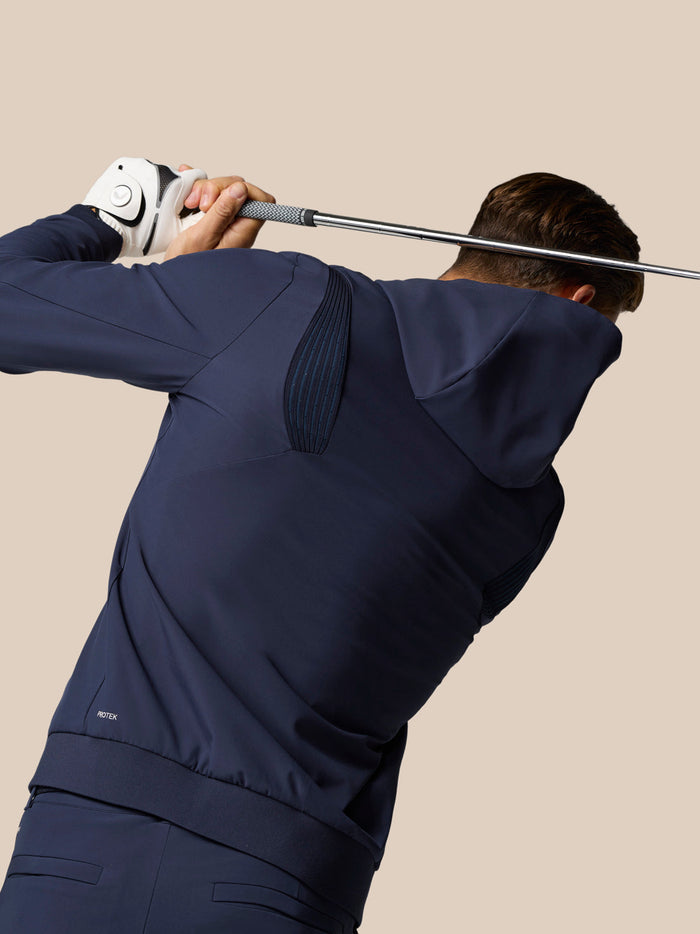 Back view of golfer in navy Golf Pinnacle Performance Hoodie during a swing with Castore logo on the chest