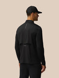 Back view of a man in a black Castore LVS golf top with back branding and layered ventilation mark
