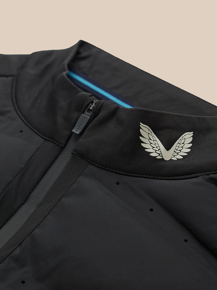 Close-up of black golf jacket collar with front zipper, white wing logo, and a blue interior stripe.