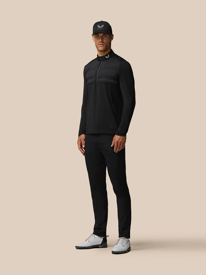 Athlete in a black Castore LVS top mid golf swing with back branding and vent signifier