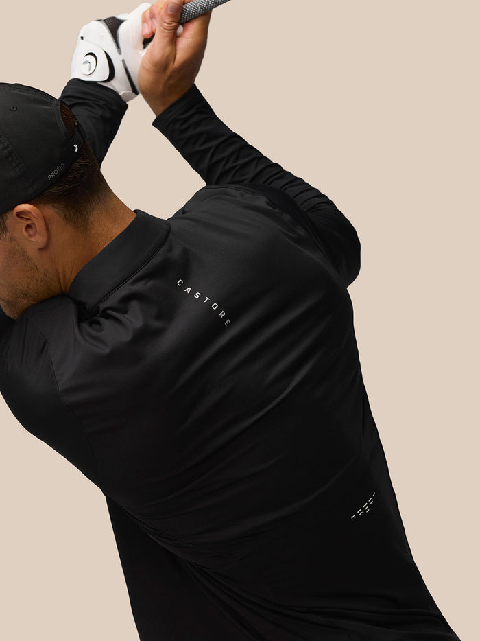Side profile of a man wearing a black LVS golf top with neck and back branding, and a cap