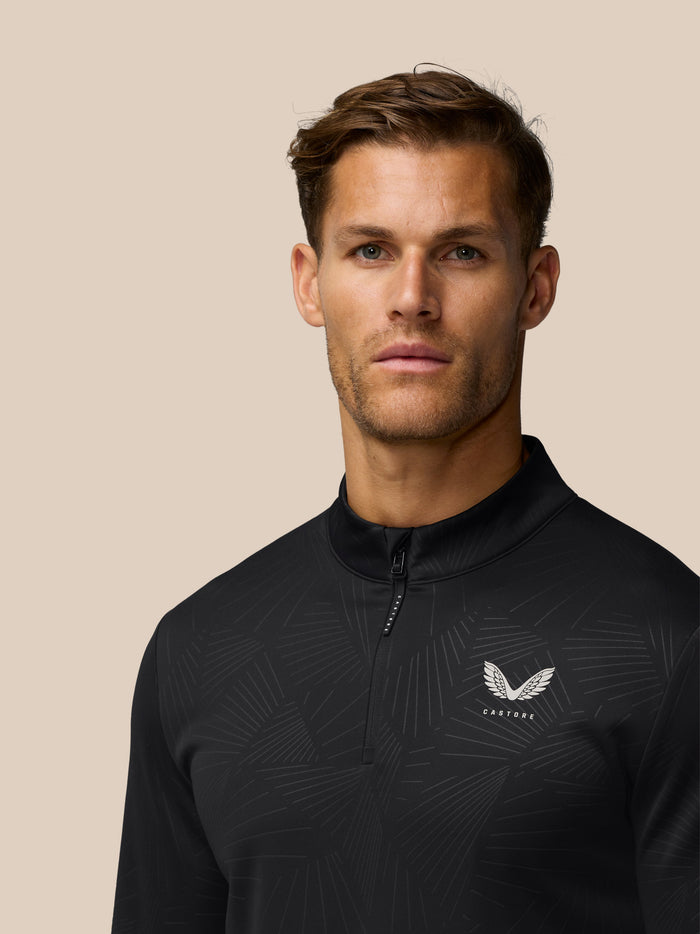 Male model wearing a black Golf Club Classic quarter zip top with a subtle embossed pattern and a white Castore wing logo on the chest