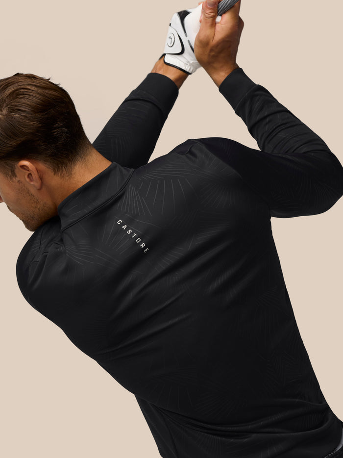 Golfer in a black Castore golf top with a subtle linear pattern and visible Castore branding on the back