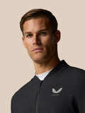 Close-up of a man wearing a black Castore golf jacket with a left chest logo