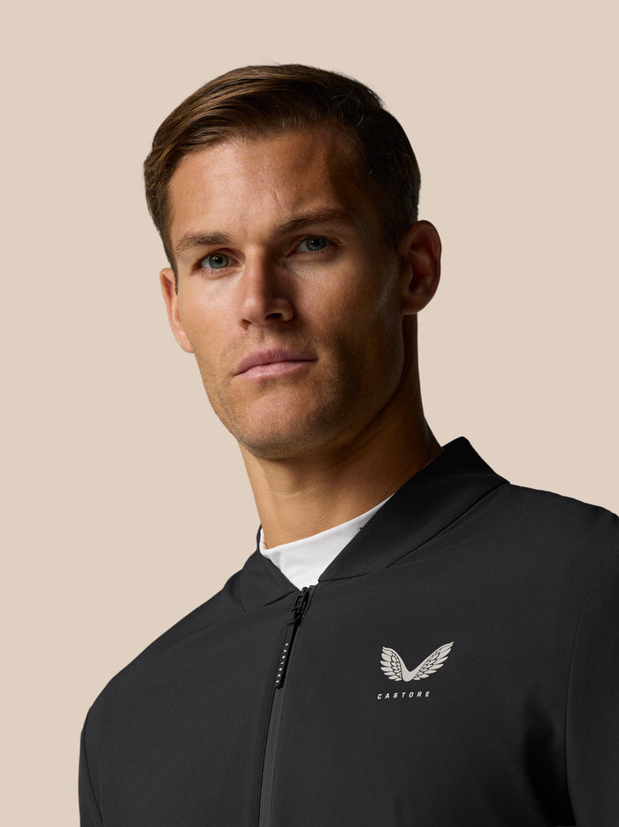 Close-up of a man wearing a black Castore golf jacket with a left chest logo