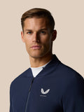 Rear view of a man in midnight navy LVS jacket with branding along the back and a golf club resting on his shoulders