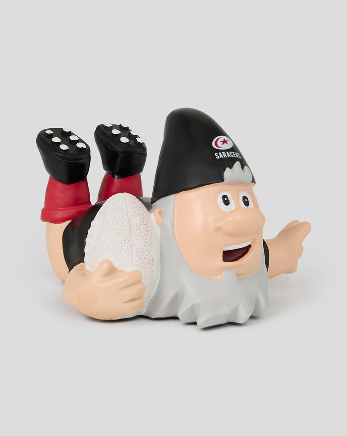 Saracens Striker Gnome lying on its stomach holding a rugby ball