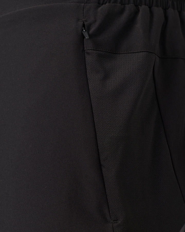 Detail of the lower side of black Saracens shorts showing a mesh panel and coral pink crescent and star logo near the hem
