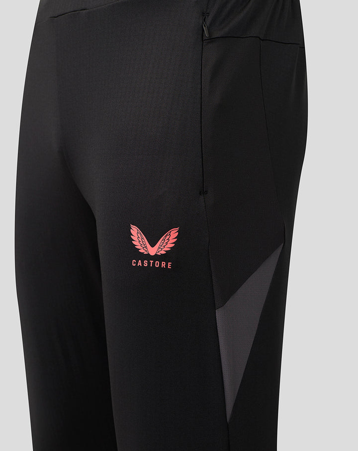 Close up of black Saracens training pants showing a pink crest and Castore branding on the thigh beside a pocket zipper.