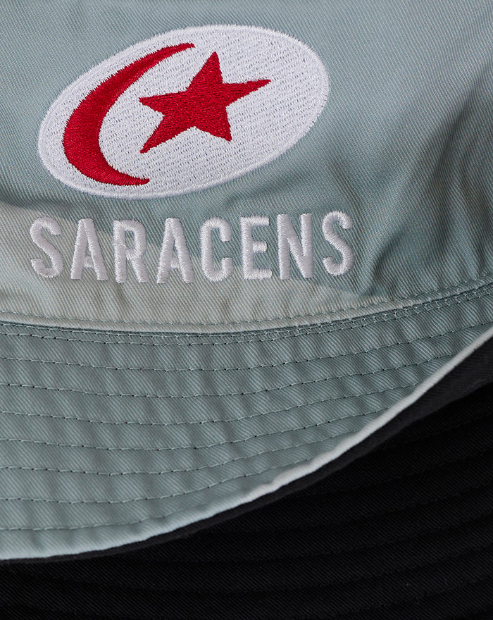 Close-up of a light blue Saracens bucket hat showing a red crescent and star patch with SARACENS embroidery.