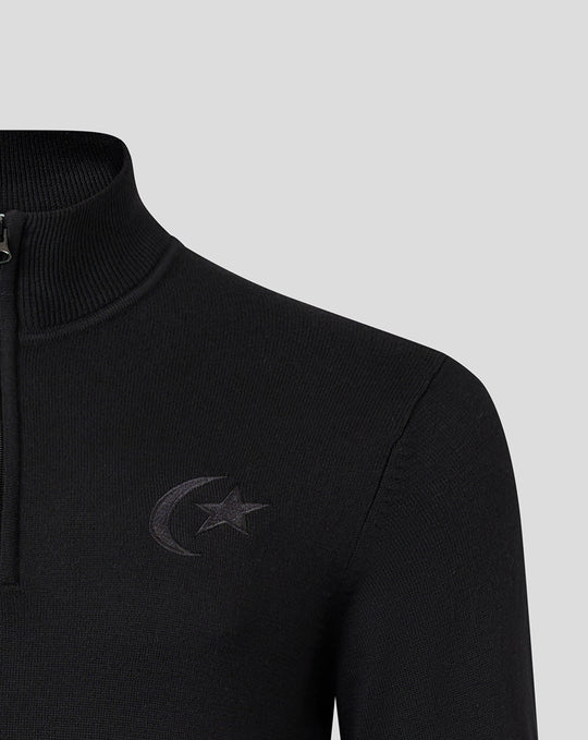 Close up of a black knit quarter zip showing tonal Saracens crest and Castore branding on the chest.