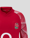 Close up of the red England junior pre match drill top showing the rose badge on the chest and a geometric sleeve design