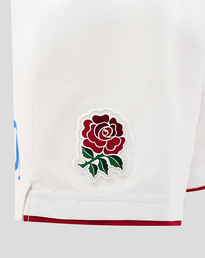 Close-up of white shorts showing embroidered red rose crest on the lower left leg