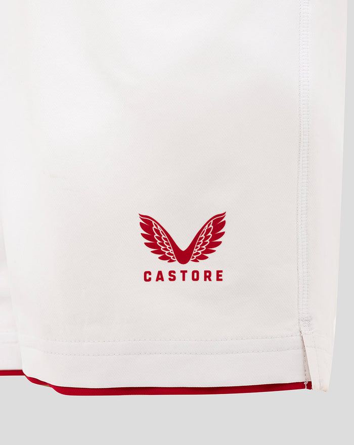 Close-up of brilliant white junior England rugby shorts fabric showing a red Castore crest near the hem and a visible side seam.