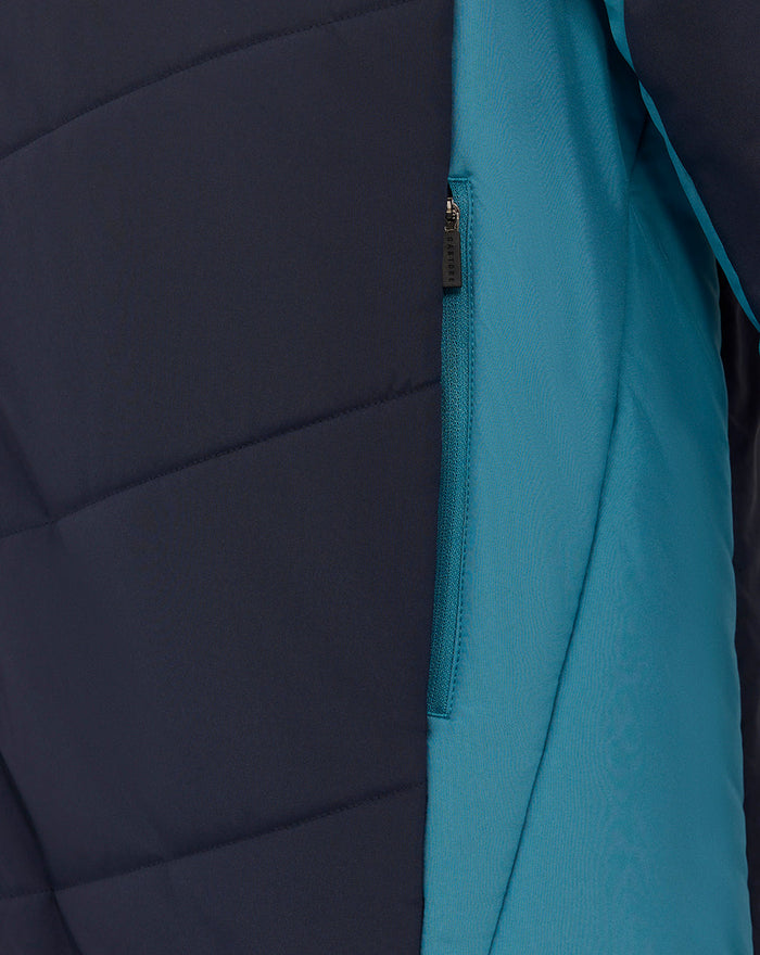 Close-up of navy and teal padded jacket showing teal zip pocket and color-block panels