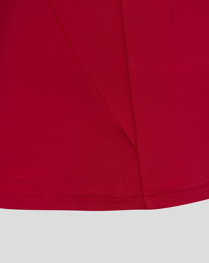 Close up of red fabric with stitched seams and curved hem from the England pre match drill top O2
