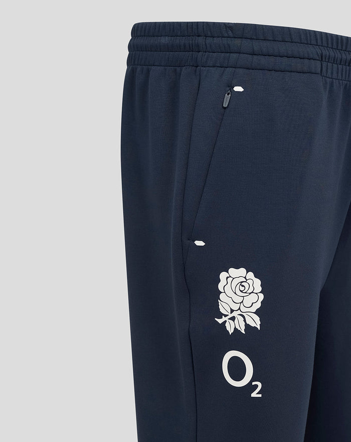 Close up of navy Travel Knit pant showing zip pocket and O2 rose emblem on the thigh with ribbed waistband.