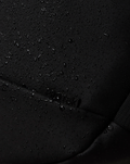 Close-up of black waterproof fabric with scattered water droplets on CORE BACKPACK