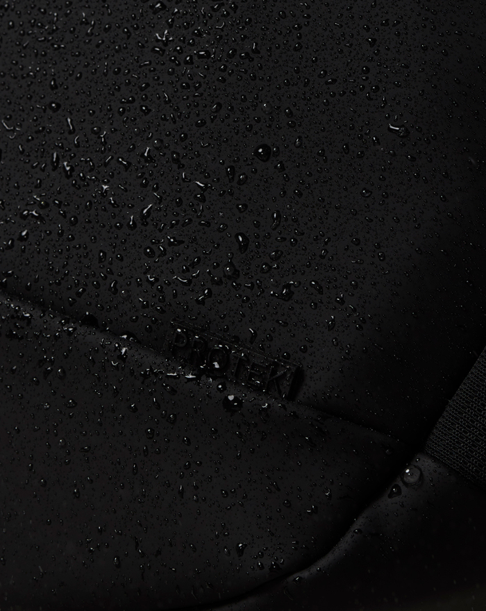 Close-up of black waterproof fabric with scattered water droplets on CORE BACKPACK