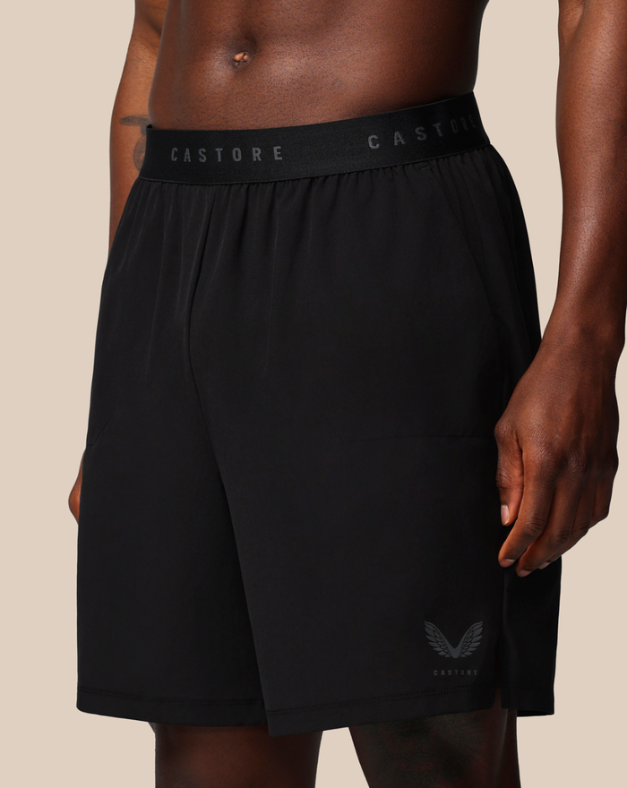 Side view of black branded elastic shorts with a Castore logo on the waistband