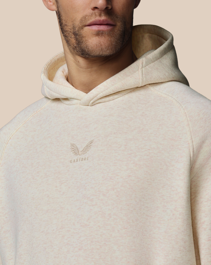 Close-up of beige flecked fabric with embroidered chest logo on hoodie